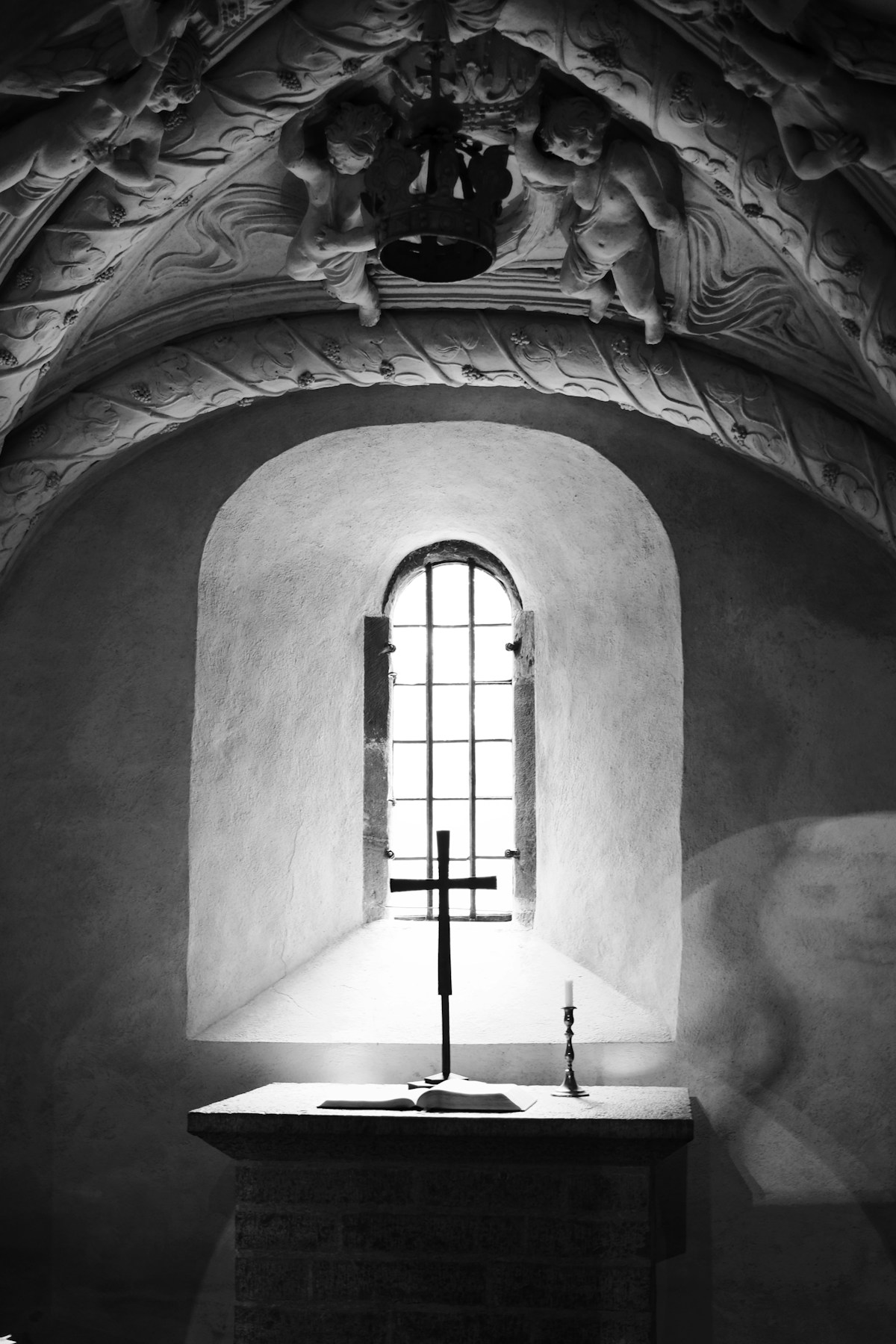 A cross, candle and open book beneath a monastery window in Varnhem, Sweden