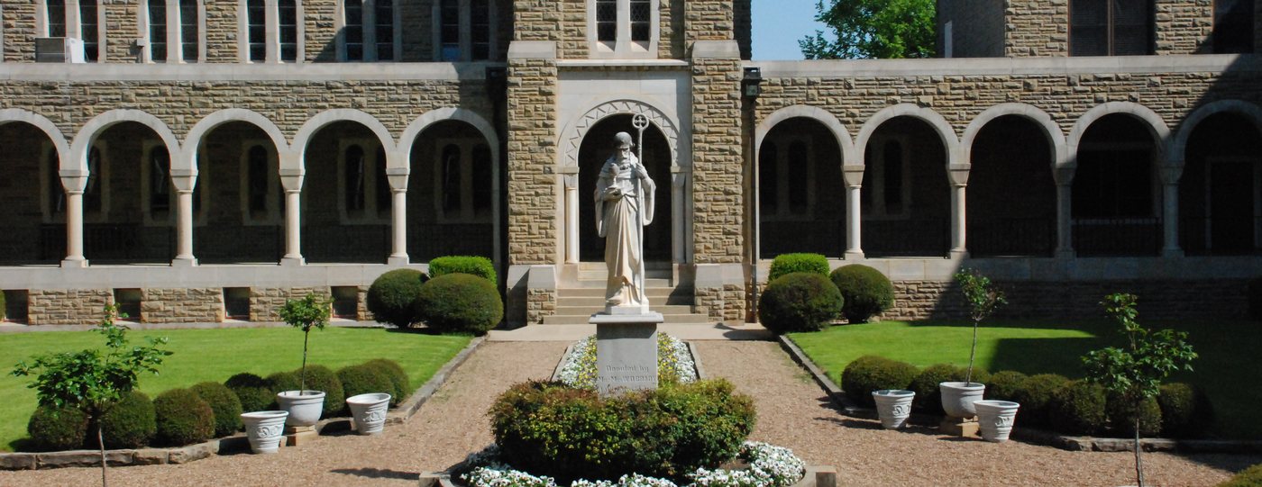 Stone arcades and a central statue overlooking the garden courtyard at Subiaco Abbey, Arkansas.