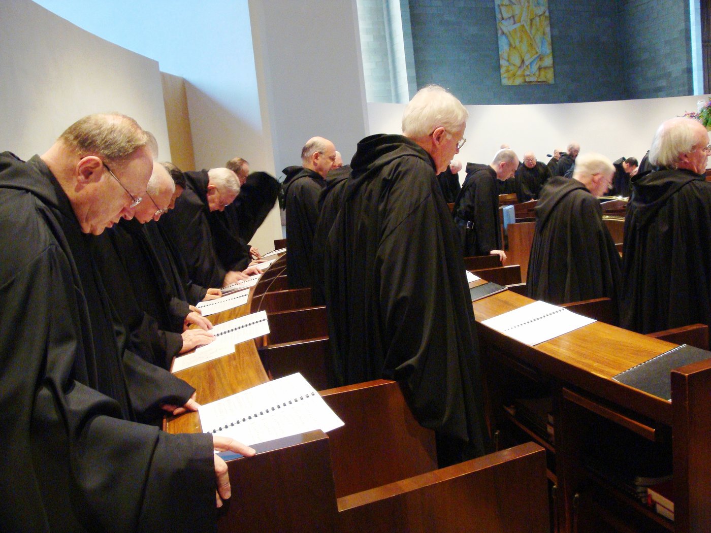 Benedictine monks in black habits praying from open books during Vespers at St. Mary’s Abbey, Morristown.